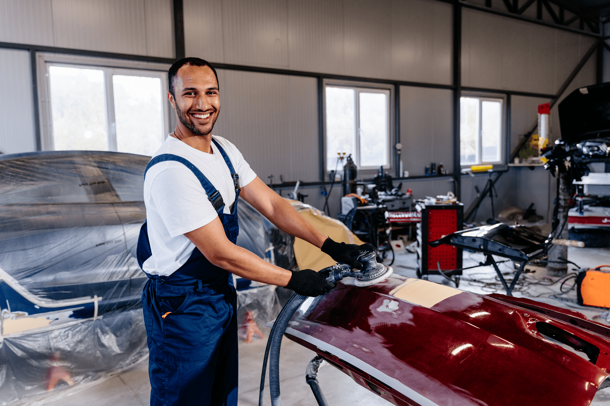 Mechanic polishing red car bumper indoors.