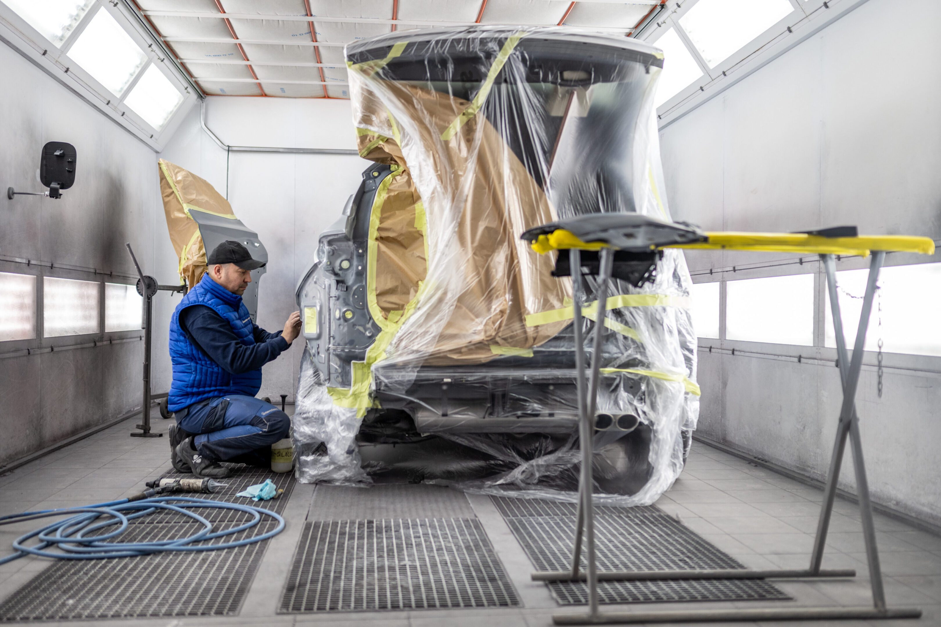 Person working on car in paint booth.