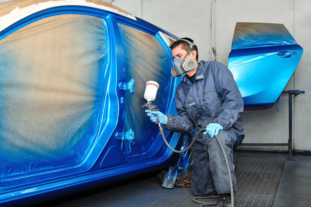 Man spray-painting a car blue.